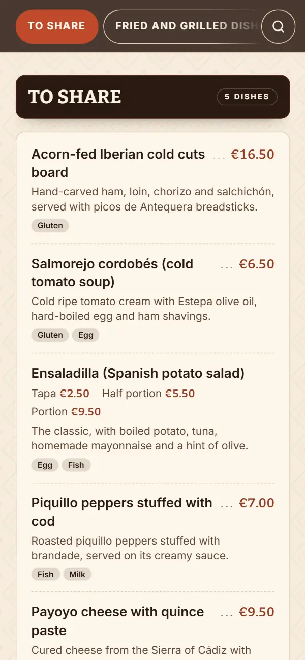 Carta de un bar de tapas en inglés en el móvil: sección To share con el Salmorejo cordobés (cold tomato soup), la Ensaladilla (Spanish potato salad) y los precios en formato inglés